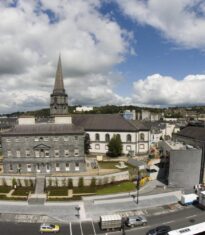 "Bishop's Palace in Viking Triangle, Waterford City with a view of a historic building, greenery, and a path in the foreground."